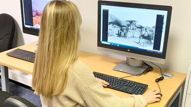 Someone sits at a computer viewing digital archives