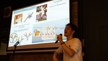 Nikolas Stefandis standing in front of a projector and speaking into a microphone