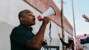 A man speaking through a megaphone to a crowd of protesters