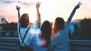 Three young women raising their hands in celebration