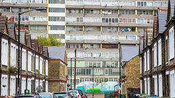 a block of flats overlooks a street with parked cars